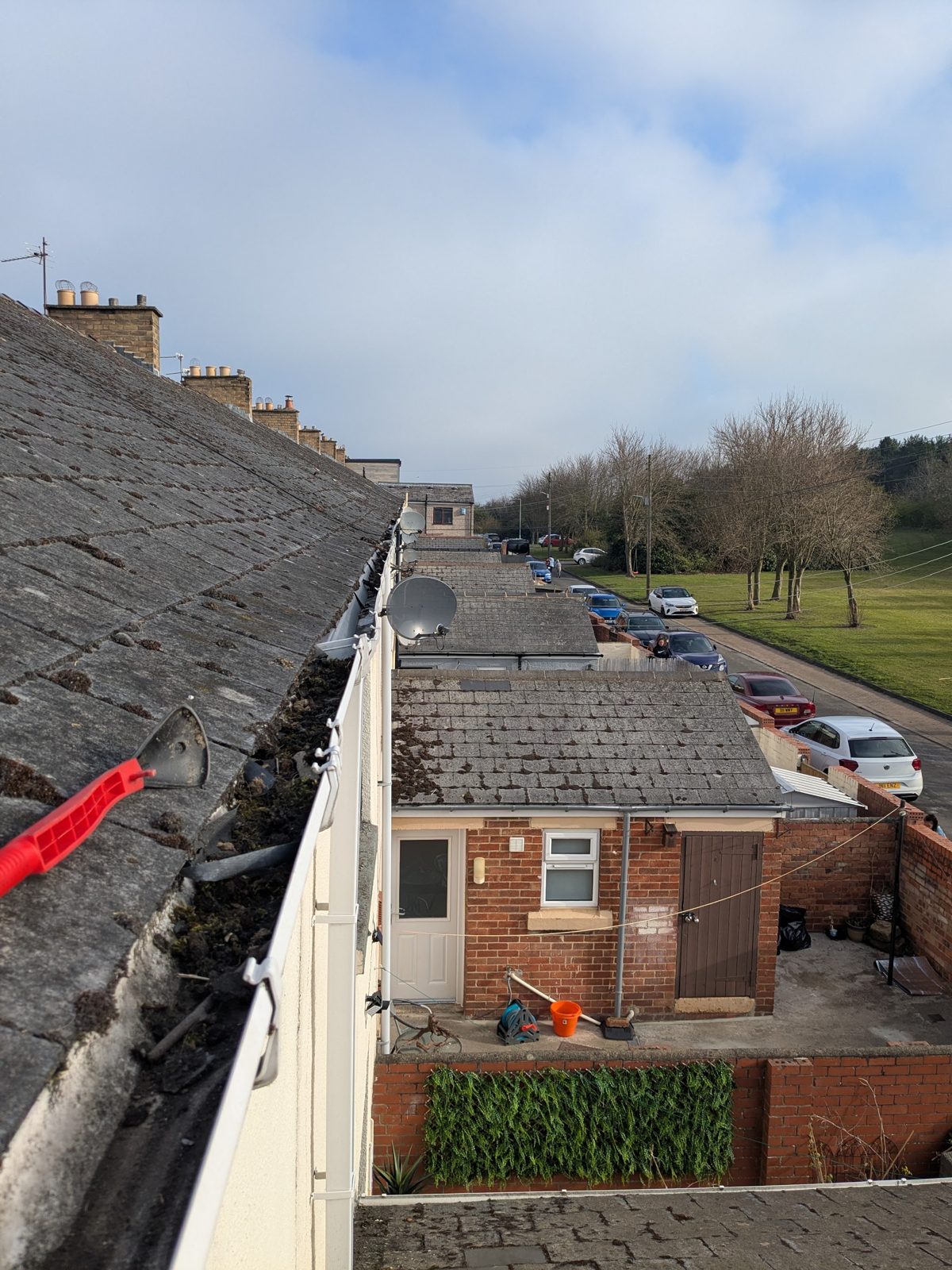 Looking along a terrace roof while clearing the gutters